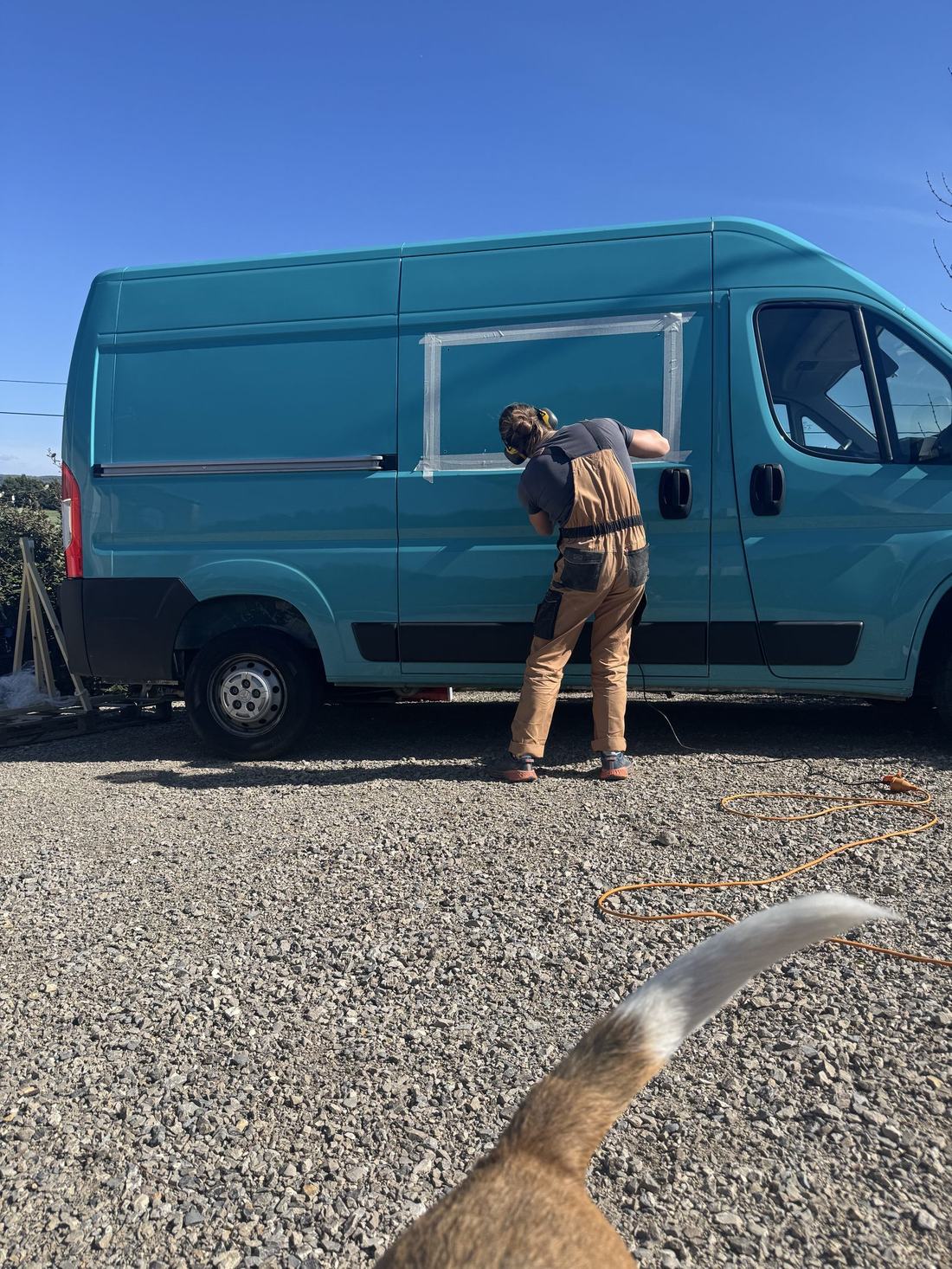 Benoît en train de préparer une fenêtre sur le van turquoise de Louise